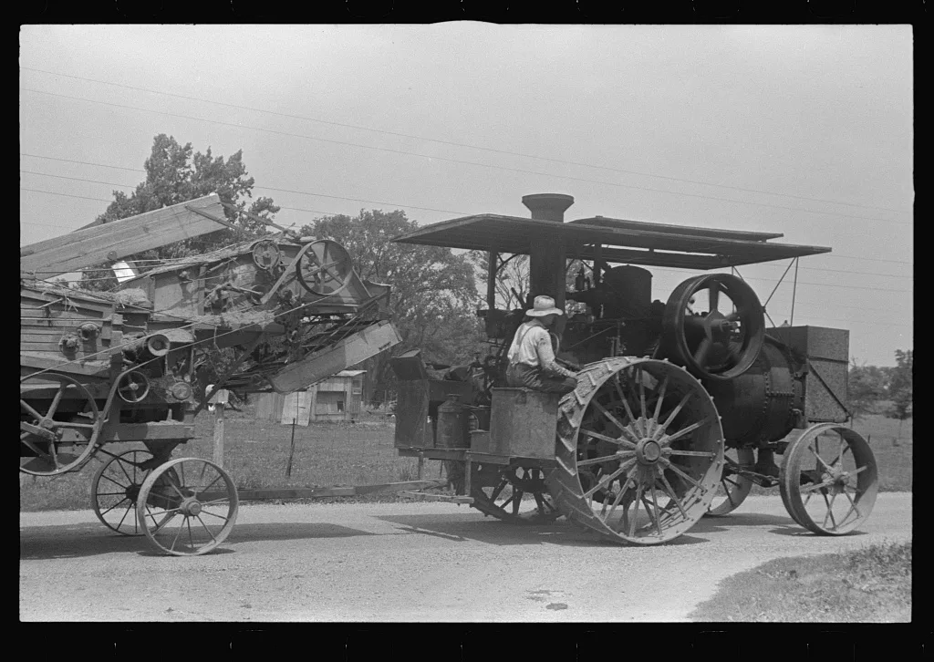 Steam tractor pulling grain separator along country road, central Ohio, 1938